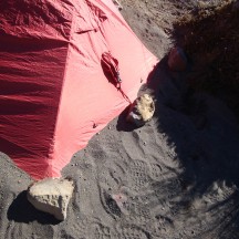 Stacking sand over the sides of the flysheet to avoid the wind turning the tent into a giant red kite.